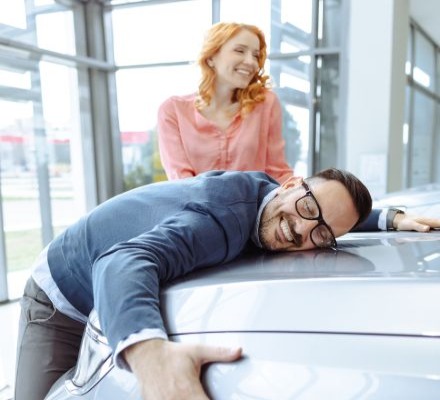 couple in dealership, man hugging car